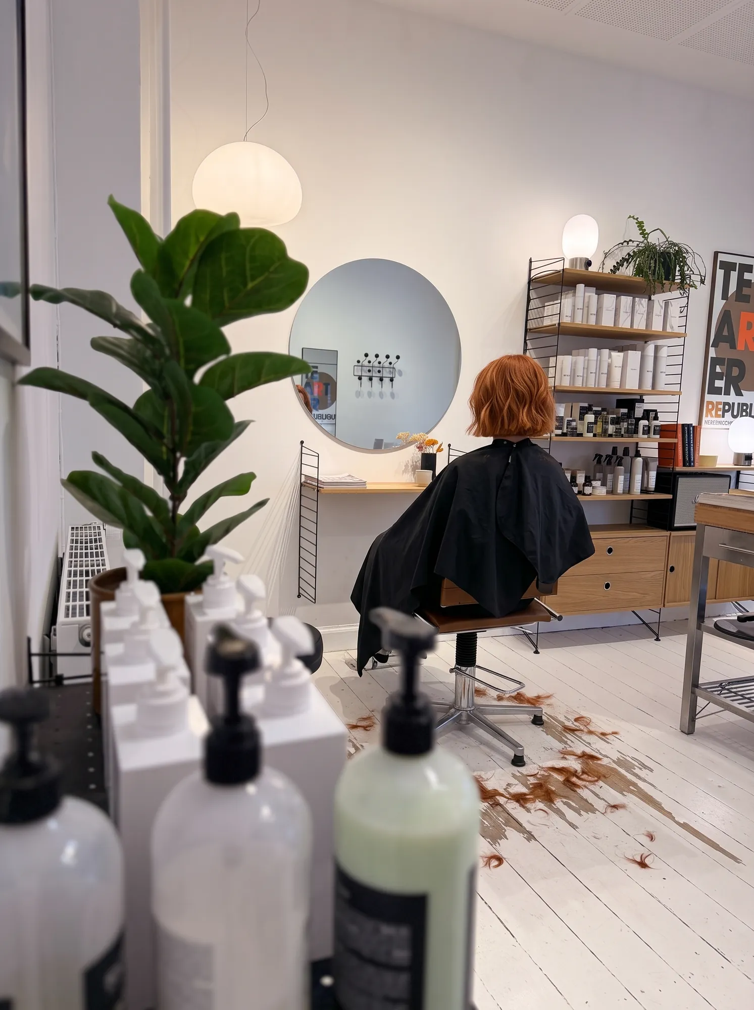 Kvinde med rødt hår og frisørkappe i salonen hos Frisør Tronborg
