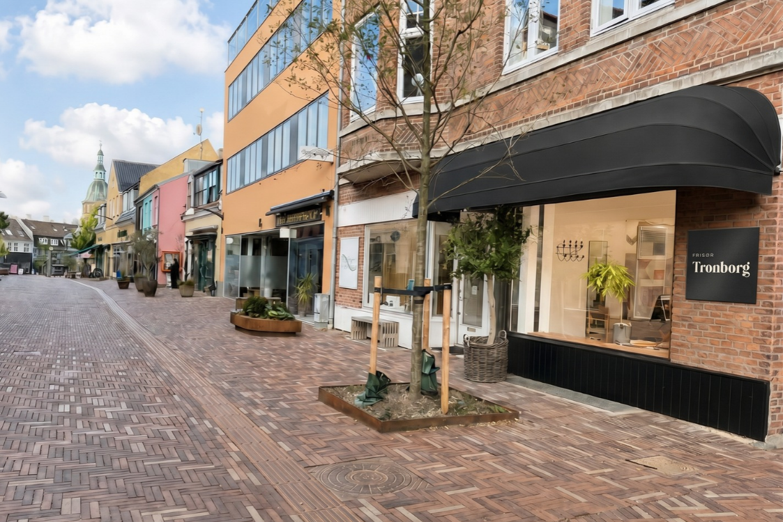 Frisør Tronborg set fra gågaden i Helsingørsgade, Hillerød, med sort markise og træ foran vinduet